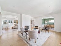 Modern living room with white walls, wood floor, chairs, coffee table, and large windows.