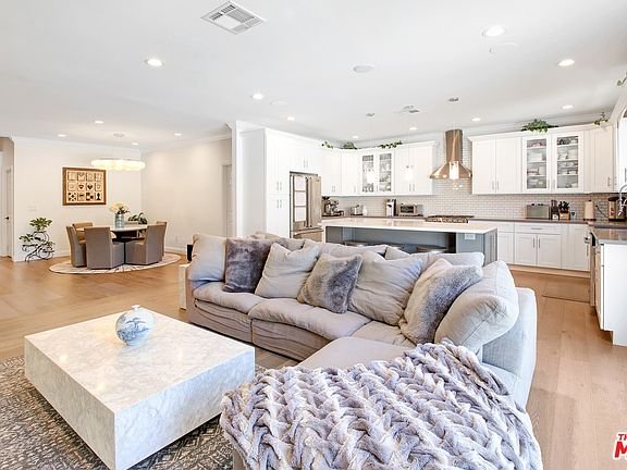Living room with sectional sofa, marble coffee table, rug, and wood floor.