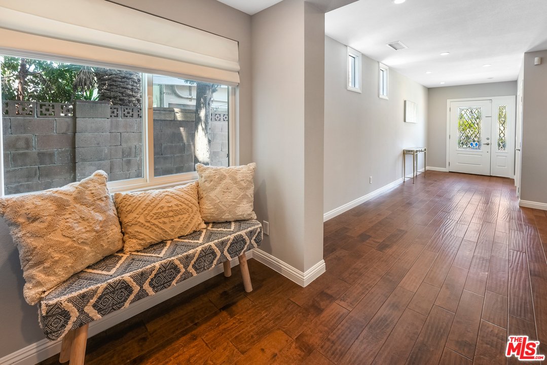Hallway with wood floor, bench with pillows, and entrance door.