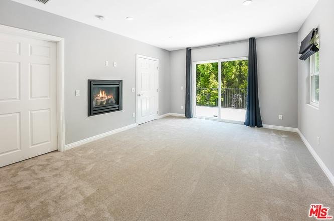 Room with gray walls, carpet floor, fireplace, and sliding glass door with curtains.