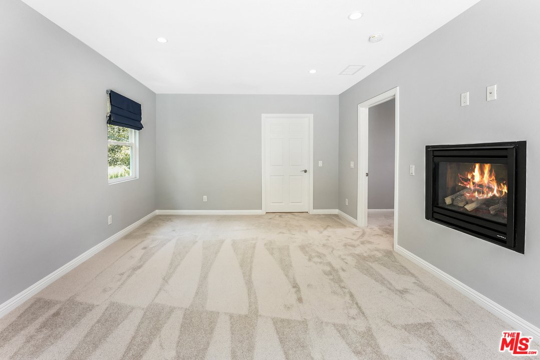 Room with gray walls, carpet floor, fireplace, window, and door.
