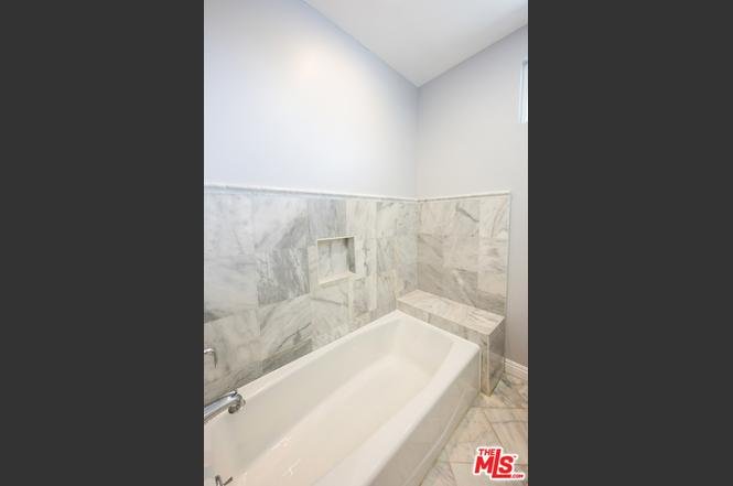 Bathroom with white bath tub and marble wall and floor tiless