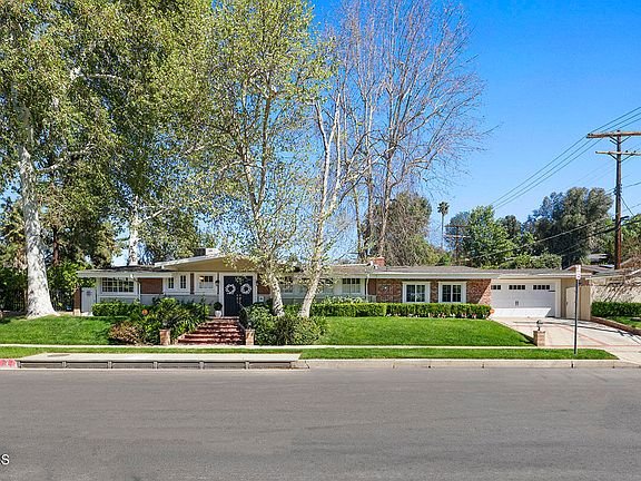 Luxury home in California real estate with lawn, trees, and driveway.