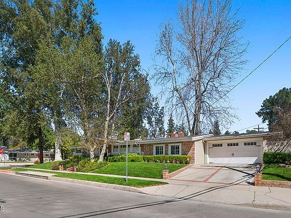 Single story house with garage, lawn, trees, on a corner lot California real estate.