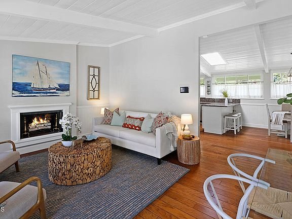 Living room with white couch, round coffee table, fireplace, sailboat wall art, and wood floor.