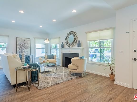 Living room with sofa, pillows, glass coffee table, rug, and lights.