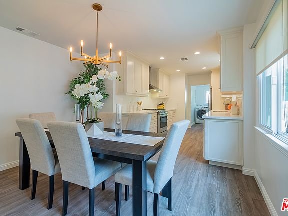 Kitchen with white cabinets, stove, wood floor, and laundry area.