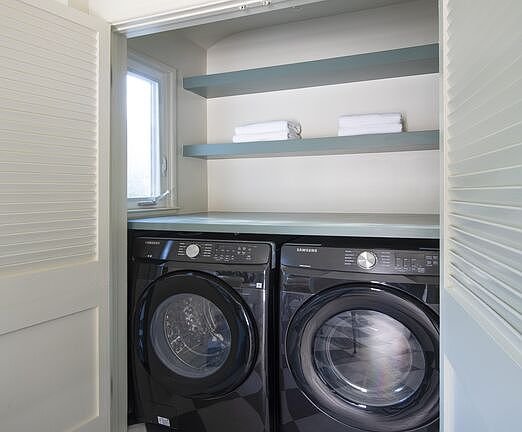 Laundry closet with stacked washer and dryer and shelves with folded towels
