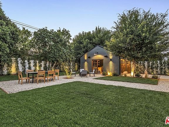 California real estate backyard with lawn, gravel pathway, dining table, and shed