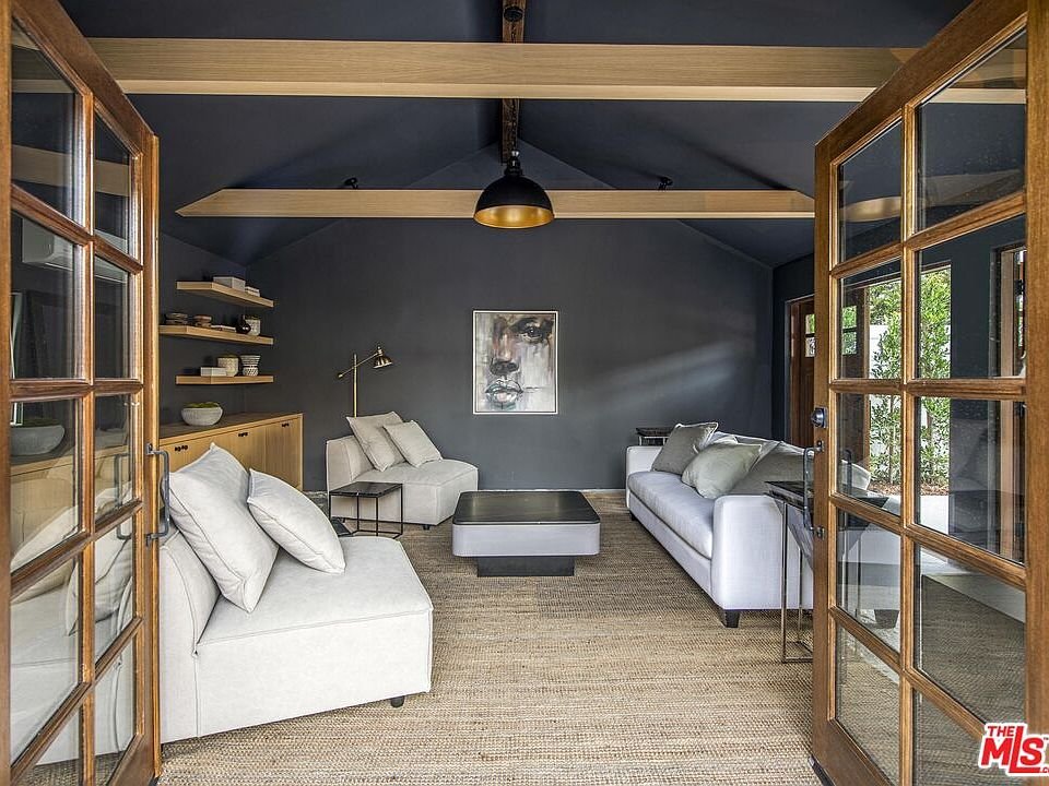 Living room with dark blue walls, white sofas, black coffee table, bookshelf, and wall artwork