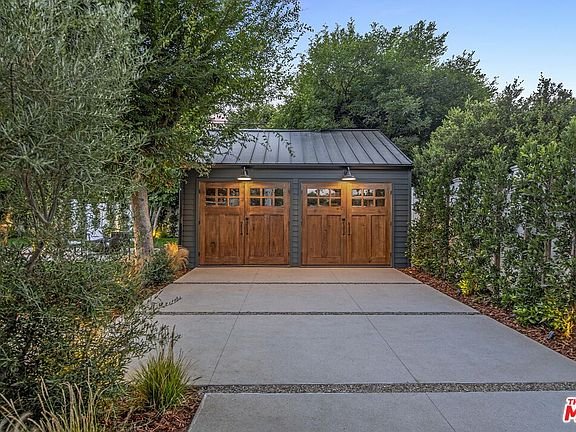 California real estate home with narrow driveway, garage, and green landscaping